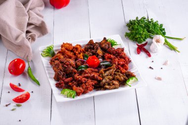 Tavuklu pakoda veya pakora, beyaz kare bir tabağa dizilmiş ve mutfak arka planında beyaz domates ve salatalıkla süslenmiş üç farklı Pakora çeşidi..