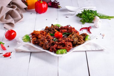 Tavuklu pakoda veya pakora, beyaz kare bir tabağa dizilmiş ve mutfak arka planında beyaz domates ve salatalıkla süslenmiş üç farklı Pakora çeşidi..