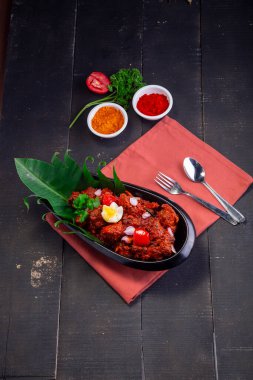 Tavuk Peralan veya tavuk köri, kerala özel tavuk tabağı oval şekilli ve muz yaprağıyla kaplanmış ve çiçek şeklinde yumurta ve soğan aromalı siyah arka planda masa pıhtısıyla kaplanmış siyah bir masa örtüsü ile güzelce düzenlenmiştir.