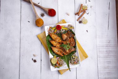 Pomfret masala veya meen pollichadu, baharat kullanan özel kerala yemeği ve muz yaprağıyla kaplanmış, salata ve limon dilimleriyle süslenmiş beyaz desenli arka planda bir sofra takımı..