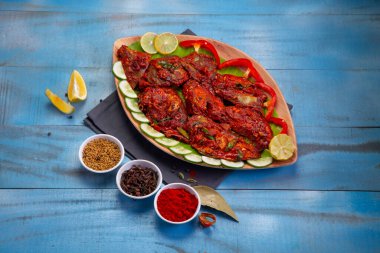 Kerala özel balık masalası aroma için baharat, hindistan cevizi dilimleri ile yapılır ve güzel bir sofra takımına yerleştirilir ve mavi desenli arka planda salatalık ve domates dilimleri ile süslenir..