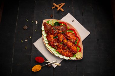 Kerala özel balık masalası aroma için baharat, hindistan cevizi dilimleri ile yapılır ve güzel bir sofra takımına yerleştirilir ve siyah desenli arka planda salatalık ve domates dilimleri ile süslenir..