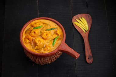 Karidesli mango körisi, çiğ mango kullanılarak yapılan kerala geleneksel yemeği ve siyah desenli toprak kaplama malzemesi.