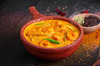 Karidesli mango körisi, çiğ mango kullanılarak yapılan kerala geleneksel yemeği ve siyah desenli toprak kaplama malzemesi.