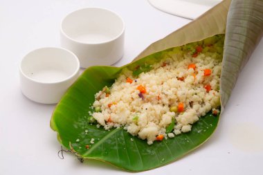 Samolina ya da rava upma 'dan yapılmış, en ünlü Güney Hindistan kahvaltı öğesi, beyaz arka planda boş küçük bir kaseyle muz yaprağında güzelce düzenlenmiş..