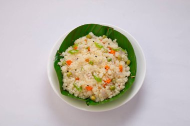 Samolina veya rava 'dan yapılmış upma, Güney Hindistan kahvaltı öğesi muz yaprağından yapılmış bir kasede güzelce düzenlenmiş ve beyaz desenli arka planda kızarmış kaju fıstığı ile süslenmiş..