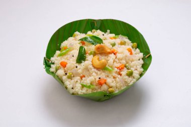 Samolina veya rava 'dan yapılmış upma, Güney Hindistan kahvaltı öğesi muz yaprağından yapılmış bir kasede güzelce düzenlenmiş ve beyaz desenli arka planda kızarmış kaju fıstığı ile süslenmiş..