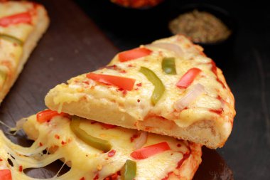 Pizza _ Paneer Makhani, ev yapımı lezzetli pizza kırmızı ve yeşil dolma biber, soğan ve mozzarella peyniri, ince hamur dilimleri ile ahşap bir tahta üzerine yerleştirilmiş gri arka plan