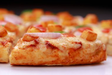 Pizza _ Paneer Makhani, kırmızı ve yeşil dolmalık biber, soğan, mozzarella peyniri ve beyaz arka plana yerleştirilmiş ince hamur hamuru dilimleri kullanılarak yapılan ev yapımı lezzetli pizza.