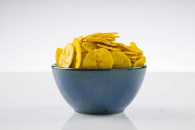 Kurutulmuş muz cipsi ya da muz waffle 'ı, beyaz desenli arka planda, su kırsal seramik kasede güzelce dizilmiş..