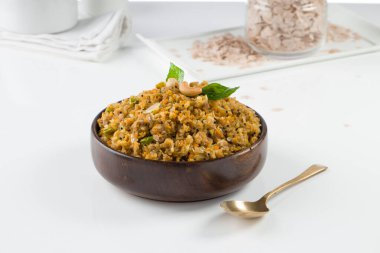 Aval upma ya da poha upma ya da kanda poha upma, çok lezzetli ve pişirmesi kolay olan sağlıklı Hint kahvaltı öğesi ve beyaz desenli arka planlı ahşap bir kasede düzenlenmiştir..