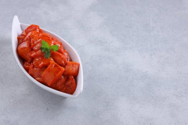 Çiğ salamura edilmiş tavuk kübü ya da beyaz seramik sofra takımına yerleştirilmiş doğranmış tavuk. Taze kişniş yaprağıyla süslenmiş. Gri beyaz desenli arka plan üzerine yerleştirilmiş..