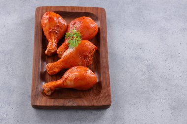 Çiğ terbiye edilmiş tavuk bacağı ya da ahşap bir zemine yerleştirilmiş bagetler. Taze kişniş yaprağı ile süslenmiş. Gri beyaz desenli arka plan üzerine yerleştirilmiş..