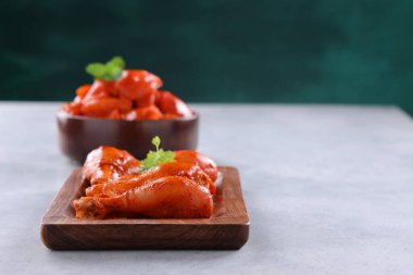 Çiğ terbiye edilmiş tavuk budu ve küpleri ahşap bir sofra takımına yerleştirilmiş taze nane yaprağıyla süslenmiş gri beyaz dokuya ve koyu yeşil arka plana yerleştirilmiş, seçici odaklı..