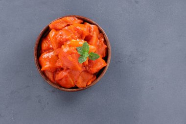 Çiğ terbiye edilmiş tavuk küpleri ahşap bir sofra takımına yerleştirilmiş taze nane yaprağıyla süslenmiş ve gri desenli arka plana yerleştirilmiş..