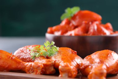 Çiğ terbiye edilmiş tavuk küpler ve bacaklar veya ahşap sofra takımına yerleştirilmiş taze kişniş ve nane yaprağı ile süslenmiş ve gri desenli arka plana yerleştirilmiş, seçici odaklı..