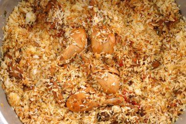 Dum tavuklu biryani, Kerala-Thalassery biryani 'nin yakın plan görüntüsü masala ve sarıyla karıştırılmış büyük alüminyum bir tencereyle ahşap desenli arka plana yerleştirilmiş..