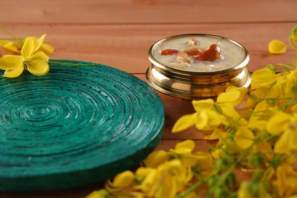 南印度的主要甜食 Vermecelli Payasam Kheer 精美地摆放在一只黄铜器皿中 绿色圆形底座放在旁边 木制底座上有金黄色的淋浴花 有选择性地聚焦 — 图库照片