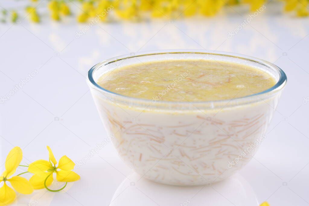 Vermecelli Payasam or Kheer ,South Indian main sweet dish made using vermicelli ,milk,sugar and dry nuts and arranged with golden shower flower in the white background, selective focus.