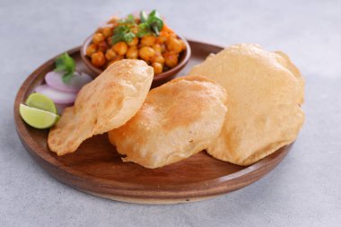 Hint kahvaltısı _ Puri ile nohut chana masala körisi, lezzetli Hint yemeği her amaçlı buğday unu kullanılıyor ahşap bir tabakta, gri desenli arka planda..