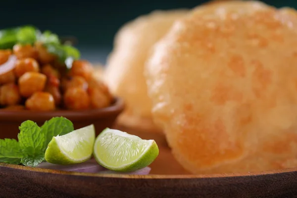 Indian breakfast _Poori with chickpea chana masala curry,tasty indian dish made using all purpose wheat flour and garnished with lemon slices and mint leaf,selective focus