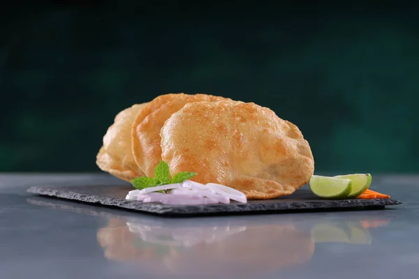 Indian breakfast _Poori or puri ,tasty indian dish made using all purpose wheat flour which is arranged in a slate with grey textured background.