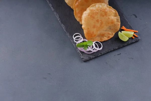 Indian breakfast _Poori or puri ,tasty indian dish made using all purpose wheat flour which is arranged in a slate with grey textured background.