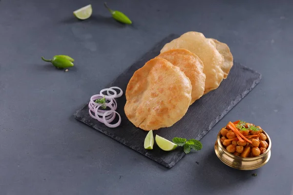 Indian breakfast _Poori or puri ,tasty indian dish made using all purpose wheat flour which is arranged in a slate with grey textured background.