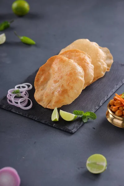 Indian breakfast _Poori or puri ,tasty indian dish made using all purpose wheat flour which is arranged in a slate with grey textured background.