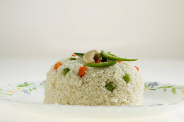 Samolina veya rava upma 'dan yapılmış upma, en ünlü Güney Hindistan kahvaltı öğesi bir tabakta güzelce düzenlenmiş ve kızarmış fındık ve köri yapraklarıyla süslenmiş beyaz arkaplan, izole edilmiş.