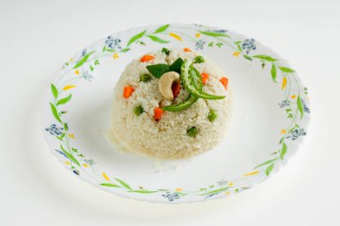 Samolina veya rava upma 'dan yapılmış upma, en ünlü Güney Hindistan kahvaltı öğesi bir tabakta güzelce düzenlenmiş ve kızarmış fındık ve köri yapraklarıyla süslenmiş beyaz arkaplan, izole edilmiş.