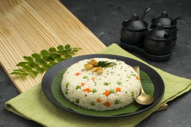 Samolina veya rava upma 'dan yapılmış upma, en ünlü Güney Hindistan kahvaltı öğesi, siyah bir tabakta düzenlenir ve kaju fıstığı ve köri yapraklarıyla süslenir..