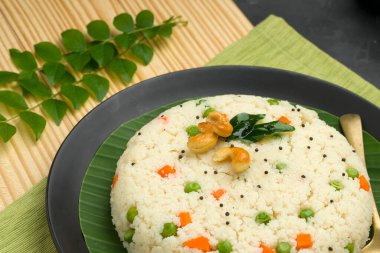 Samolina veya rava upma 'dan yapılmış upma, en ünlü Güney Hindistan kahvaltı öğesi, siyah bir tabakta düzenlenir ve kaju fıstığı ve köri yapraklarıyla süslenir..