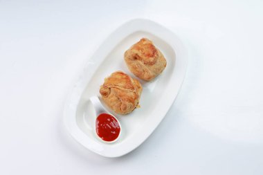 Baharatlı ve lezzetli yumurta masala ile doldurulmuş yumurtalı börek ve beyaz desenli arka planda domates soslu beyaz bir sofra takımı..