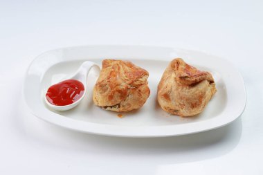 Baharatlı ve lezzetli yumurta masala ile doldurulmuş yumurtalı börek ve beyaz desenli arka planda domates soslu beyaz bir sofra takımı..