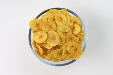 Kurutulmuş muz cipsi ya da muz waffle 'ı. Beyaz desenli, izole edilmiş cam bir kasede güzelce dizilmiş..