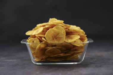 Kurutulmuş muz cipsi ya da muz waffle 'ı, cam bir kâse ya da gri desenli sofra takımında güzelce dizilmiş, izole edilmiş..