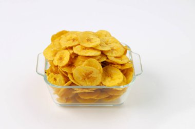 Kurutulmuş muz cipsi ya da muz waffle 'ı, cam bir kasede ya da beyaz desenli sofra takımında güzelce sıralanmış, izole edilmiş..