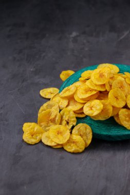 Kurutulmuş muz cipsi ya da muz waffle 'ı, gri desenli, izole edilmiş yeşil bir zemine saçılmış..