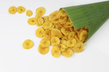 Kurutulmuş muz cipsi ya da muz waffle 'ı muz yaprağı konisinden beyaz desenli arka plana dökülmüş..
