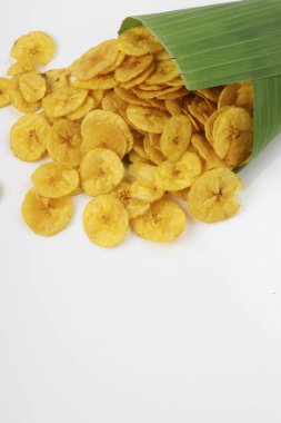 Kurutulmuş muz cipsi ya da muz waffle 'ı muz yaprağı konisinden beyaz desenli arka plana dökülmüş..