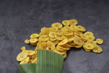 Kurutulmuş muz cipsi ya da muz waffle 'ı muz yaprağı konisinden gri desenli arka plana döküldü..