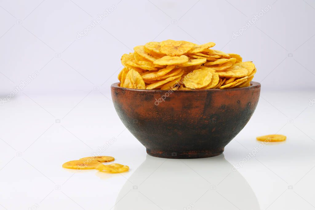 Dried banana chips or banana waffers,arranged beautifully in a clayor earthenware with white textured background, isolated.