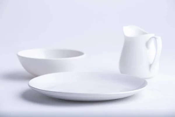 白色餐具 不同形状的空白白色陶瓷盘 碗和茶壶 放在白色纹理背景上 — 图库照片