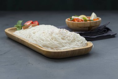 İdeyappam ya da noolappam, çiğ pirinç kullanılarak yapılan Güney Hindistan kahvaltı öğesi, gri dokulu arka planda yumurtalı masala ile ahşap servis tabanında iyi bir kombinasyon olarak düzenlenir..