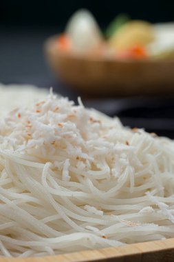 İdeyappam ya da noolappam, çiğ pirinç kullanılarak yapılan Güney Hindistan kahvaltı öğesi, gri dokulu arka planda yumurtalı masala ile ahşap servis tabanında iyi bir kombinasyon olarak düzenlenir..