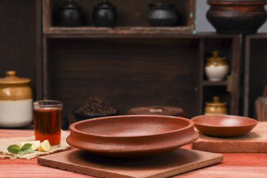 Kare bir yere yerleştirilmiş boş bir toprak eşyasının yanına limon çayı ve yanına yerleştirilmiş boş bir toprak tabakası, mutfak arka planında ahşap bir doku..