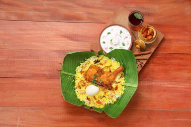 Tavuk biryani, kerala stili tavuk dhum biryani jeera pilavı ve baharatlarla raithave limon turşusuyla ahşap dokuya dizilmiştir..