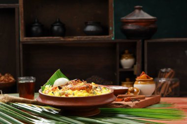 Tavuk dum biryani, limon turşusu ve raita meze olarak ve ahşap desenli sıcak limon çayı, mutfak arka planı, seçici odaklanma.