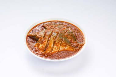 Beyaz pomfret masala körisi, Hint usulü, koyu kırmızı soslu ve yeşil biber, köri yaprakları ve beyaz arkaplanda beyaz bir seramik kasede düzenlenmiş malabar tamarind ile süslenmiş..